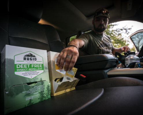 man in a car reaching out to a foil pack of a rugid sunscreen