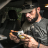 man in a car holding a foil pack of rugid sunscreen