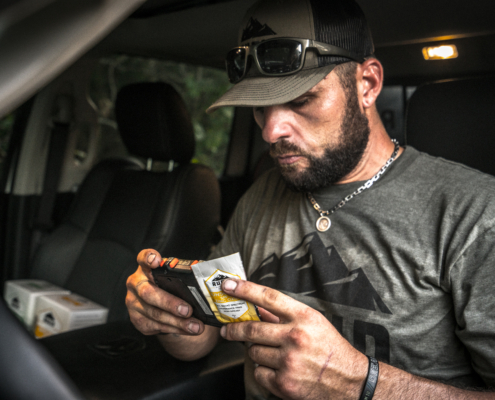 man in a car holding a foil pack of rugid sunscreen